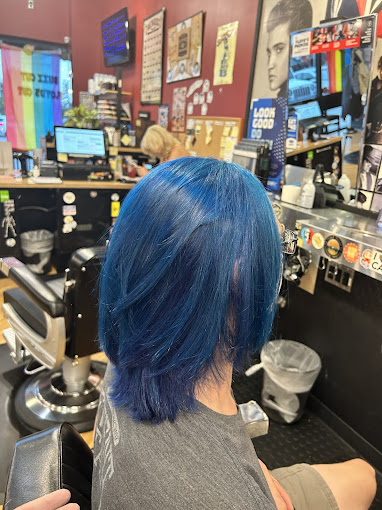 A woman with blue hair sitting in a barber shop